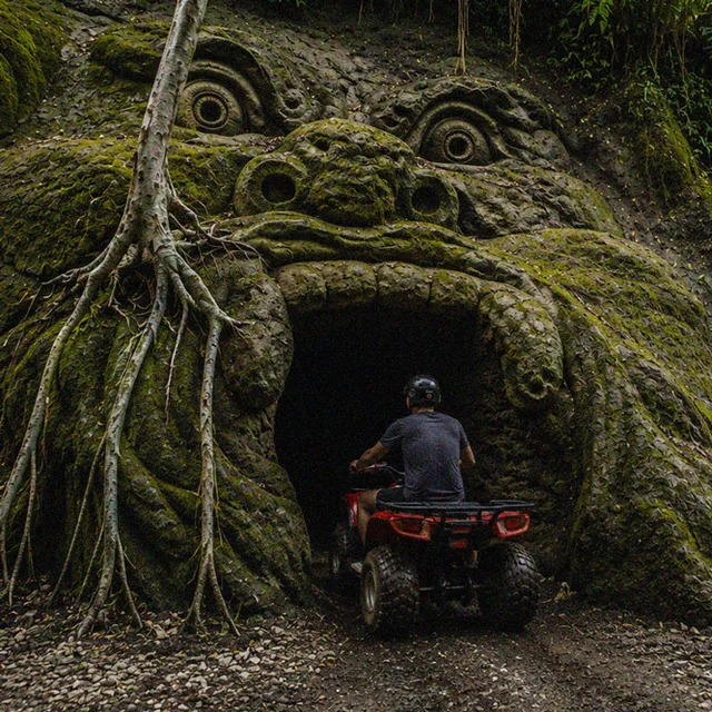 Quad bike riding into a carved jungle cave mouth